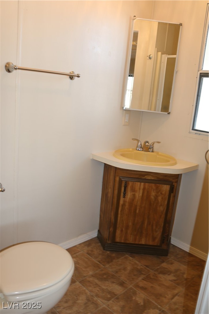 4633 Royal Ridge Boulevard Las Vegas, NV 89103 - Photo 10 of 13 Half bathroom with baseboards, toilet, vanity, and tile patterned floors