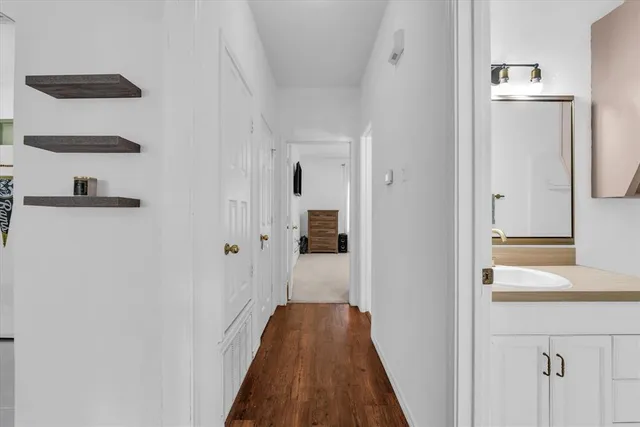 a view of a hallway with wooden floor and cabinets