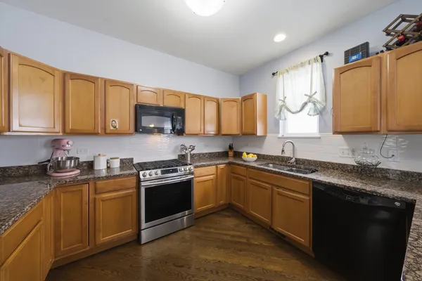 a kitchen with stainless steel appliances granite countertop a sink stove and cabinets