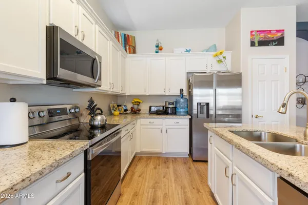 a kitchen with granite countertop stainless steel appliances a sink a stove top oven a counter space and cabinets