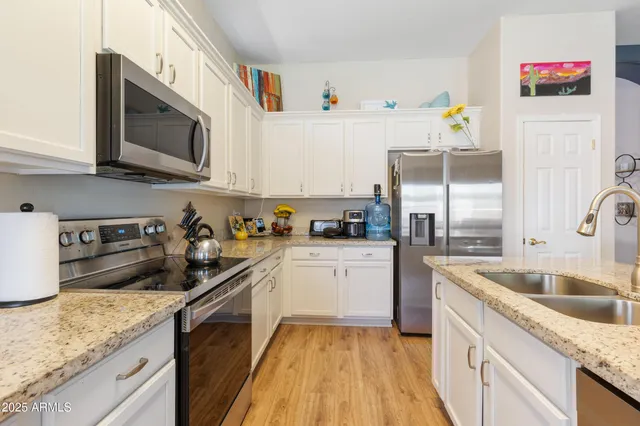 a kitchen with granite countertop stainless steel appliances a sink a stove top oven a counter space and cabinets