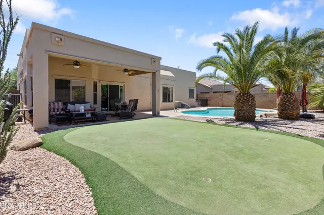 a view of swimming pool with outdoor seating and house in the background
