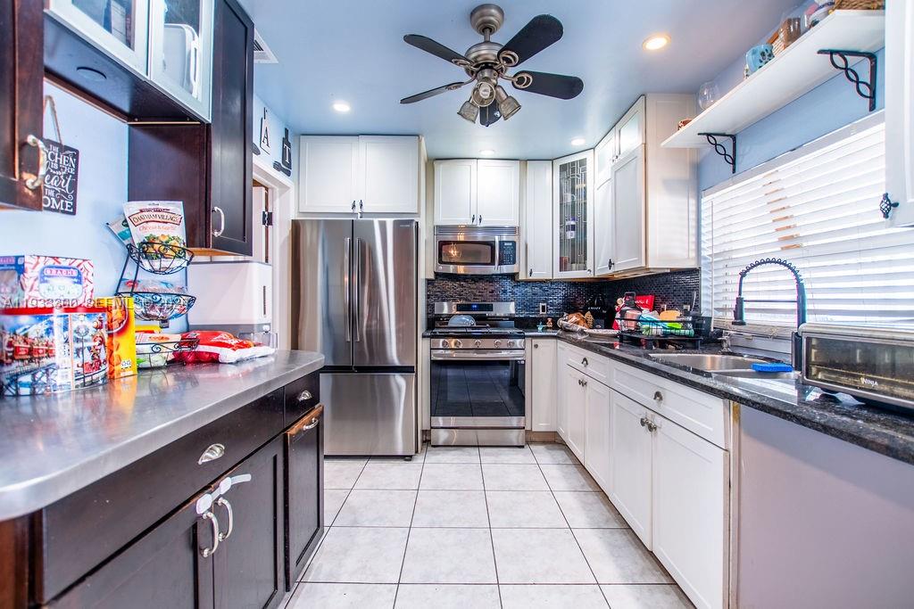 11751 Northwest 32nd Manor Sunrise, FL 33323 - Photo 9 of 32 a kitchen with stainless steel appliances kitchen island granite countertop a sink refrigerator and microwave