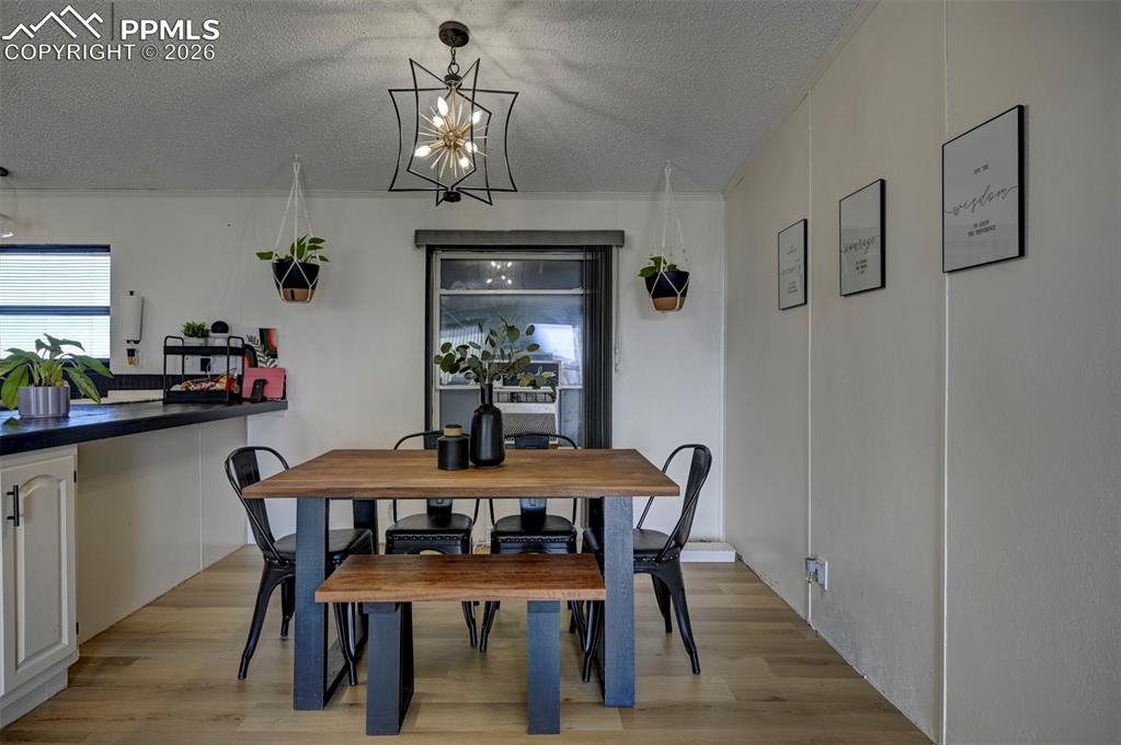 21050 McDaniels Road Calhan, CO 80808 - Photo 17 of 46 a dining room with furniture a chandelier and wooden floor