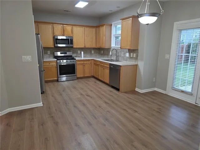 a kitchen with stainless steel appliances granite countertop a stove a sink dishwasher and a refrigerator with wooden floor