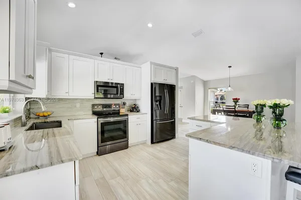 a kitchen with granite countertop a sink a counter top space appliances and cabinets