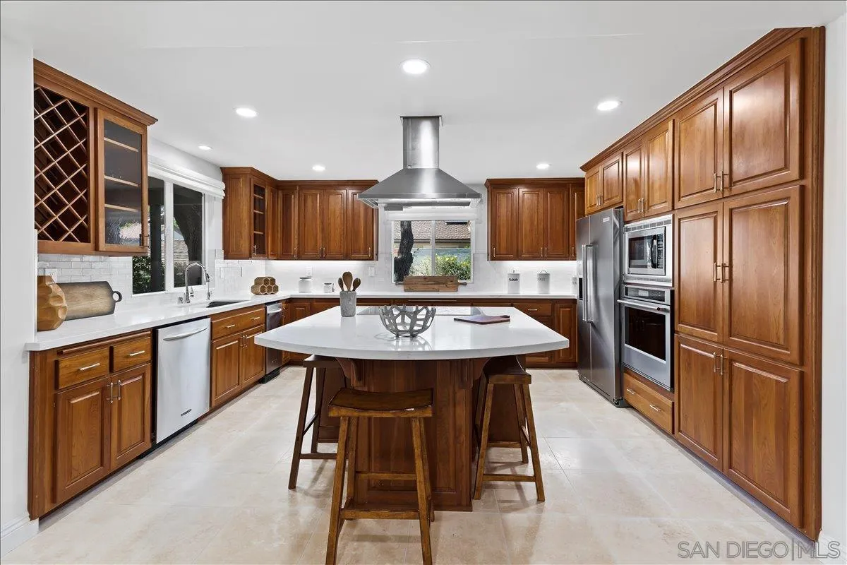 16902 Via De Santa Fe, Unit 12 Rancho Santa Fe, CA 92091 - Photo 12 of 54 a kitchen with stainless steel appliances kitchen island granite countertop a kitchen island a stove a refrigerator a oven a sink with island and chairs