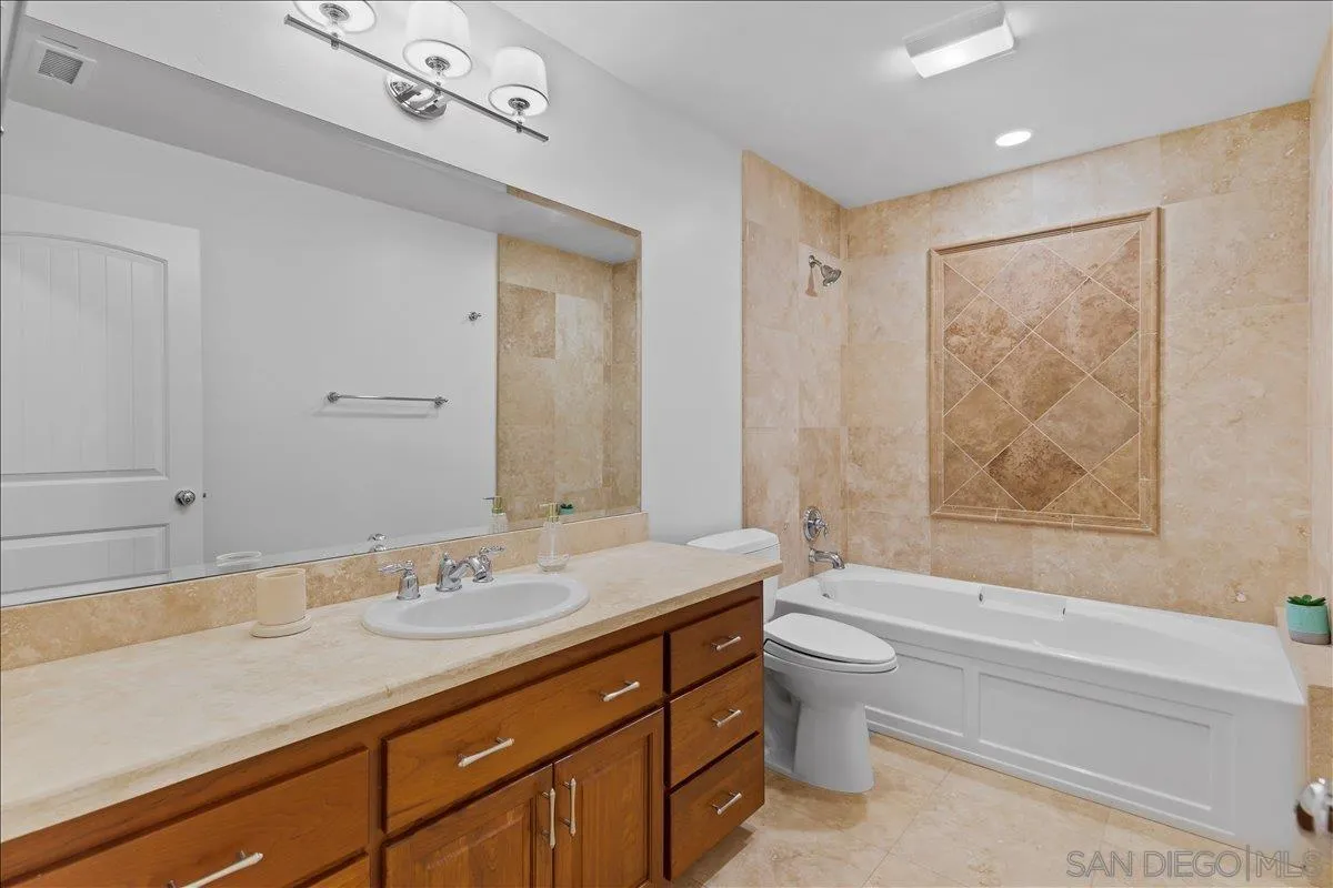 16902 Via De Santa Fe, Unit 12 Rancho Santa Fe, CA 92091 - Photo 30 of 54 a bathroom with a granite countertop sink a toilet a mirror a vanity and bathtub