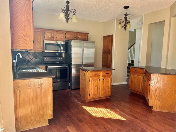 a kitchen view with wooden floor and cabinets