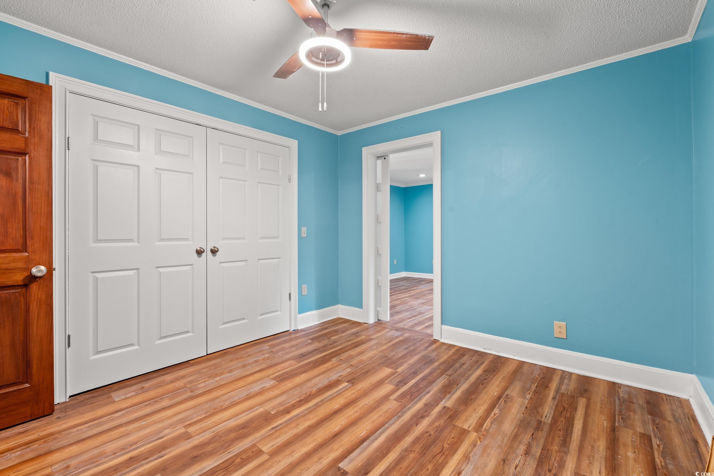 902 Palm Street Georgetown, SC 29440 - Photo 12 of 38 Unfurnished bedroom featuring a ceiling fan, wood finished floors, ornamental molding, a closet, and a textured ceiling