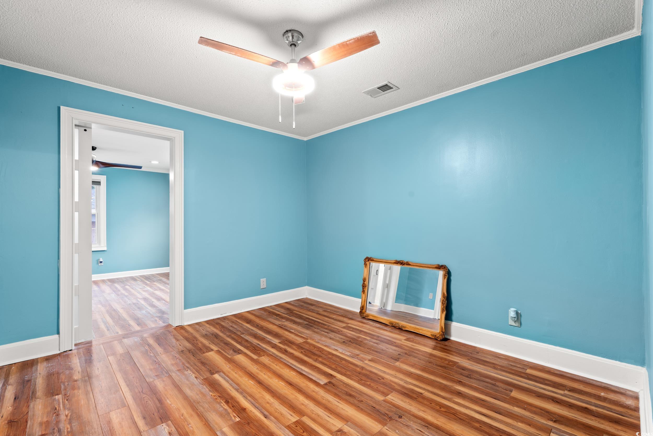 902 Palm Street Georgetown, SC 29440 - Photo 13 of 38 Unfurnished room with wood finished floors, ornamental molding, a textured ceiling, and ceiling fan