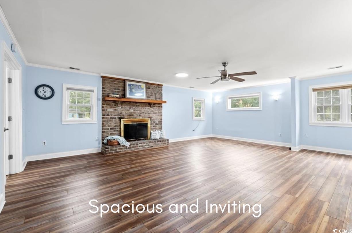902 Palm Street Georgetown, SC 29440 - Photo 2 of 38 Unfurnished living room featuring a fireplace, dark wood-style flooring, ornamental molding, and a ceiling fan