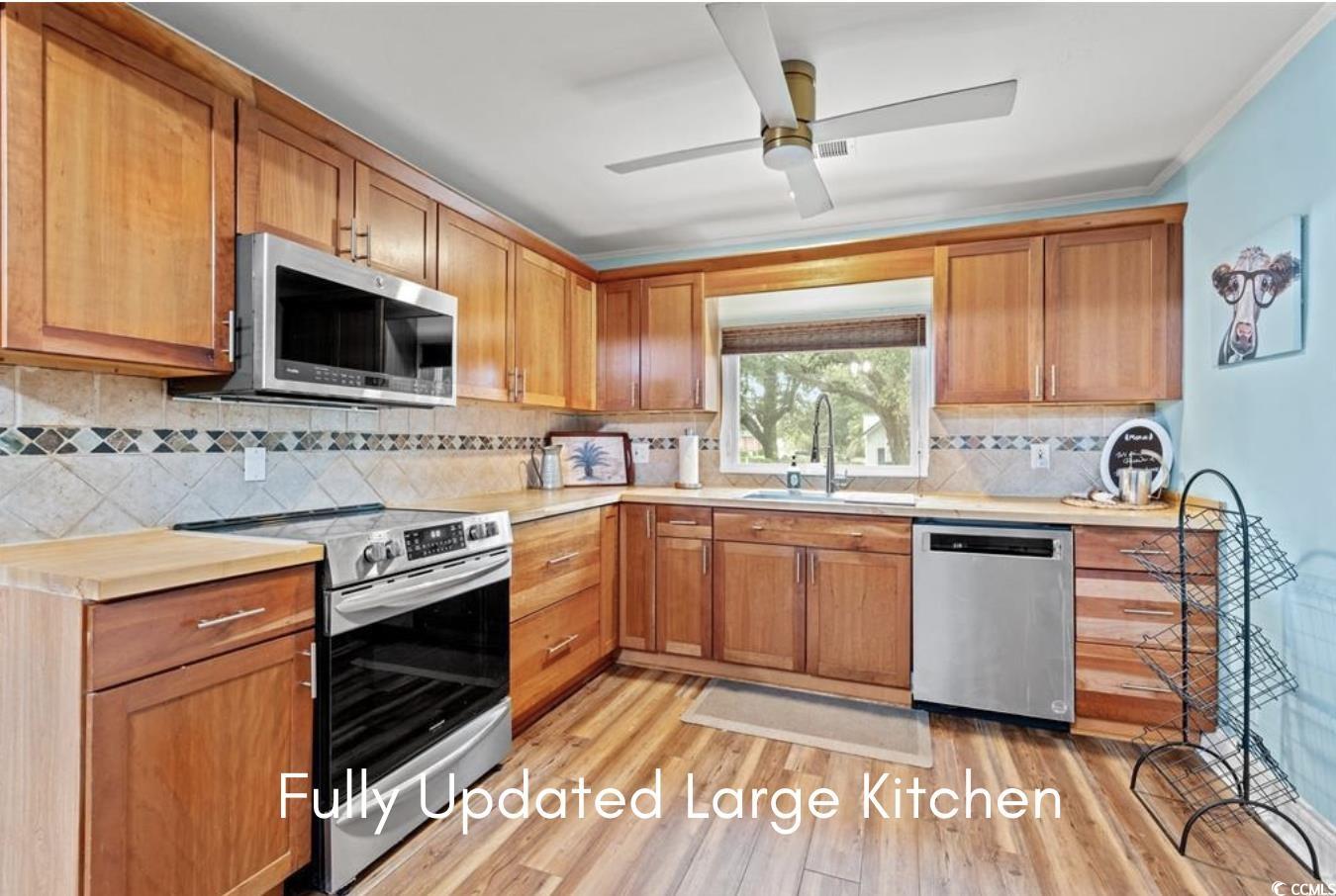 902 Palm Street Georgetown, SC 29440 - Photo 3 of 38 Kitchen with light countertops, appliances with stainless steel finishes, brown cabinetry, and decorative backsplash