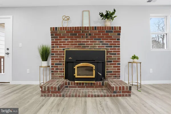 a living room with a fireplace wooden floor and a potted plant