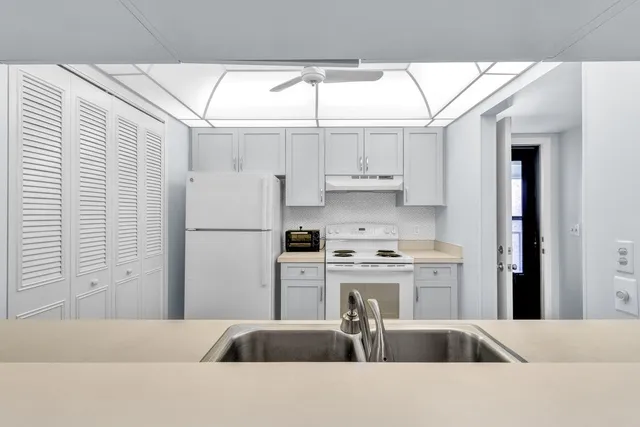 a kitchen with stainless steel appliances kitchen island granite countertop a refrigerator a sink a stove and white cabinets