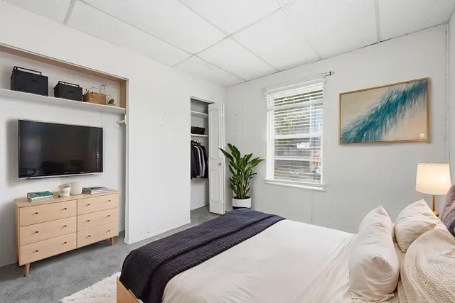 a bedroom with a bed a tv and wooden floor