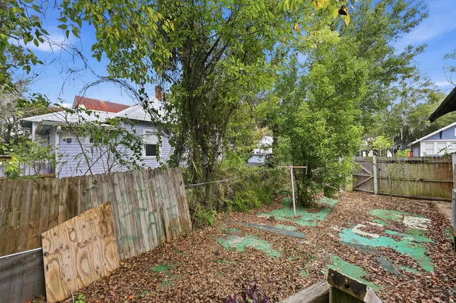 a view of a backyard with wooden fence and a large tree