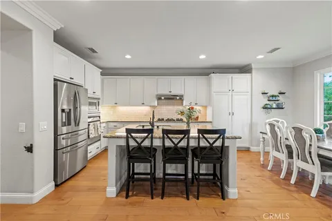 a kitchen with stainless steel appliances a dining table chairs and refrigerator