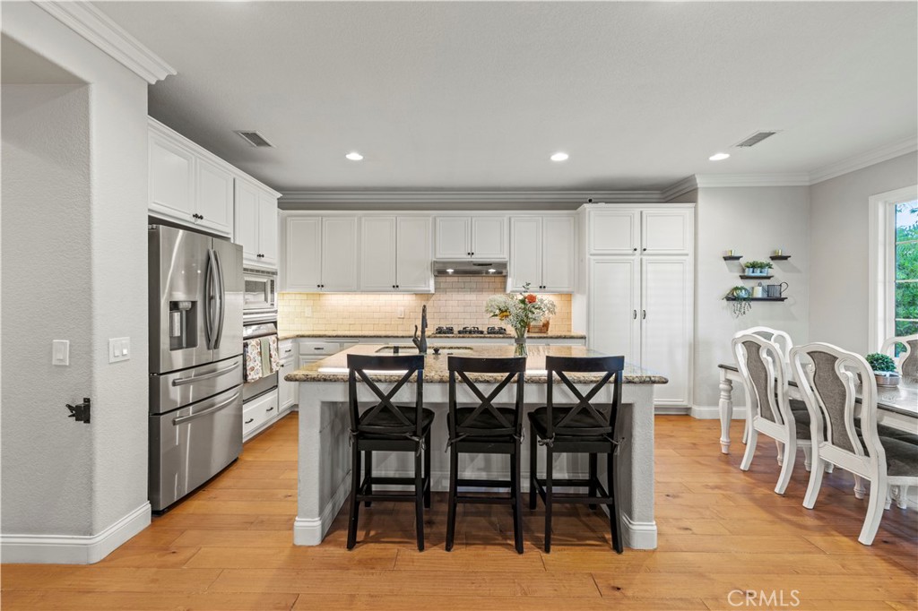 24303 Las Palmas Street Valencia, CA 91355 - Photo 7 of 34 a kitchen with stainless steel appliances a dining table chairs and refrigerator