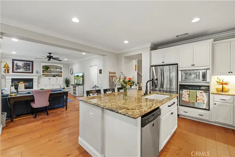 a kitchen with stainless steel appliances granite countertop a sink dishwasher and a refrigerator with wooden floor