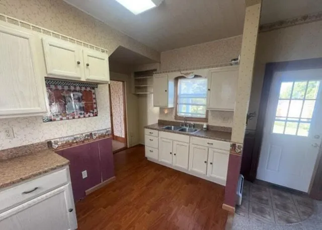 a kitchen with granite countertop a sink cabinets and wooden floor