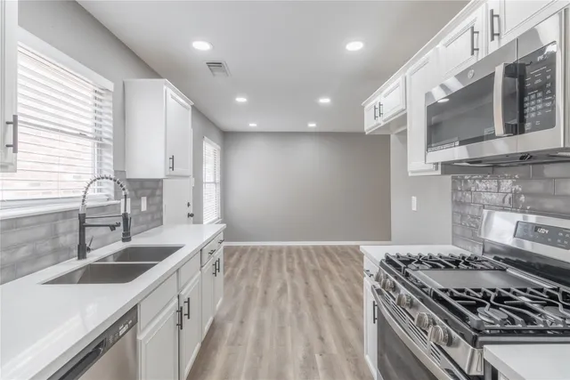 a kitchen with kitchen island granite countertop a sink stainless steel appliances and cabinets