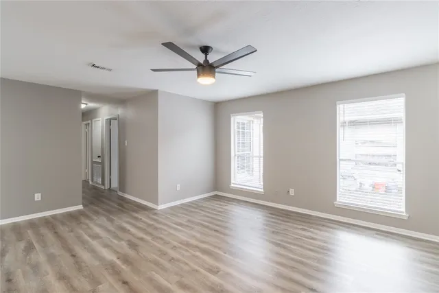 a view of an empty room with a window and wooden floor