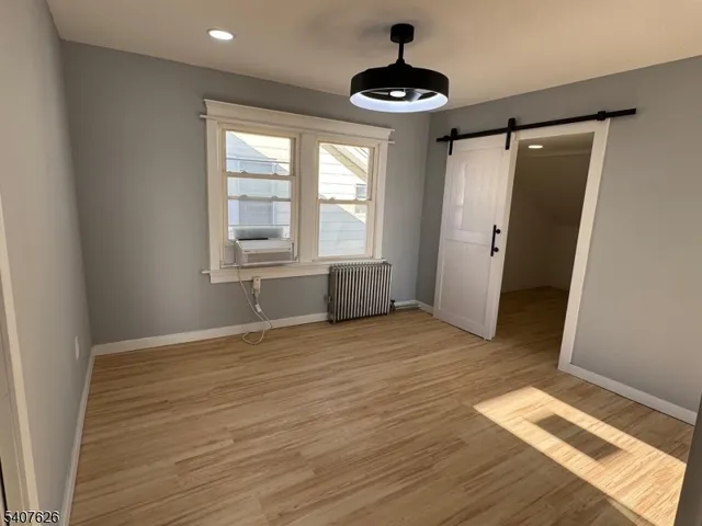 a view of an empty room with window and hardwood floor