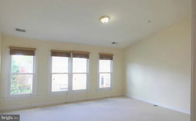 a view of an empty room with a window and a kitchen
