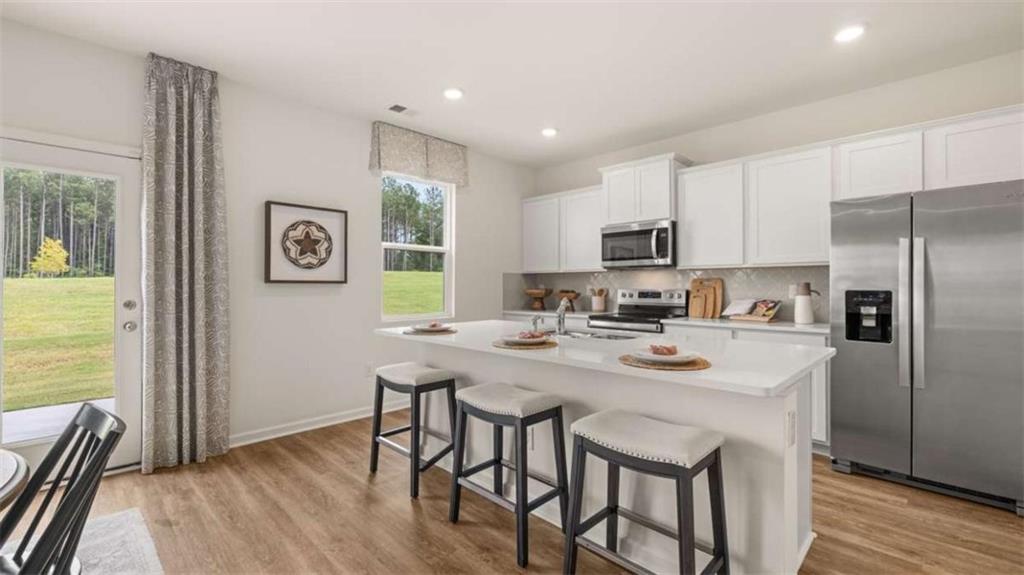 330 Friendship Oak Way Hampton, GA 30228 - Photo 7 of 41 a kitchen with stainless steel appliances granite countertop a stove a refrigerator a sink a dining table and chairs with wooden floor