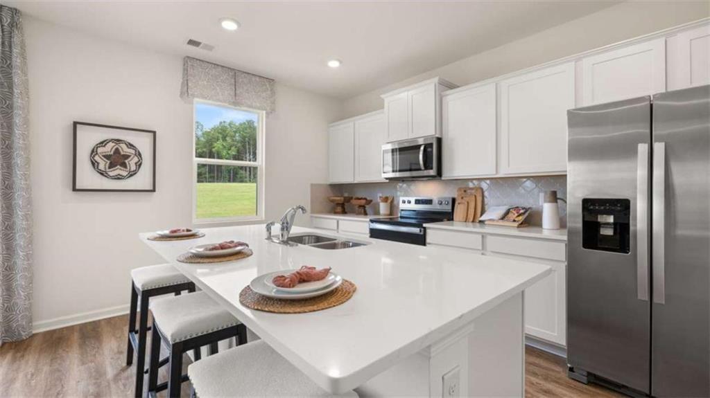 330 Friendship Oak Way Hampton, GA 30228 - Photo 9 of 41 a kitchen with a refrigerator a stove a sink and a dining table with wooden floor