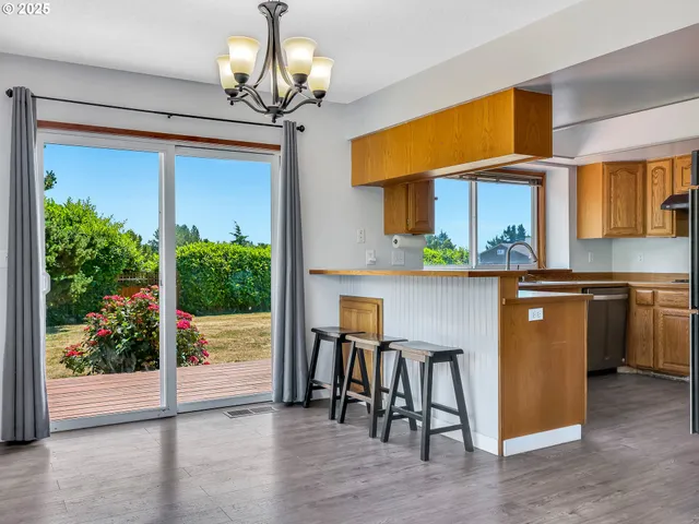 a kitchen with stainless steel appliances granite countertop a stove top oven a sink with dining table and chairs