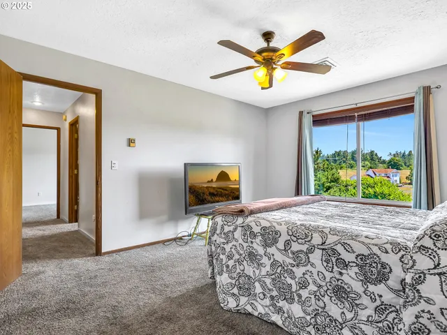 a living room with a bed a flat screen tv and a large window