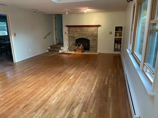 a view of a livingroom with wooden floor and a fireplace