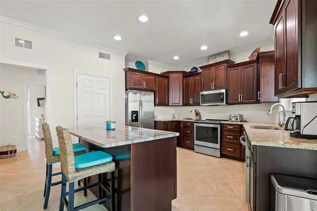 a kitchen with stainless steel appliances granite countertop a stove top oven a sink a dining table and chairs