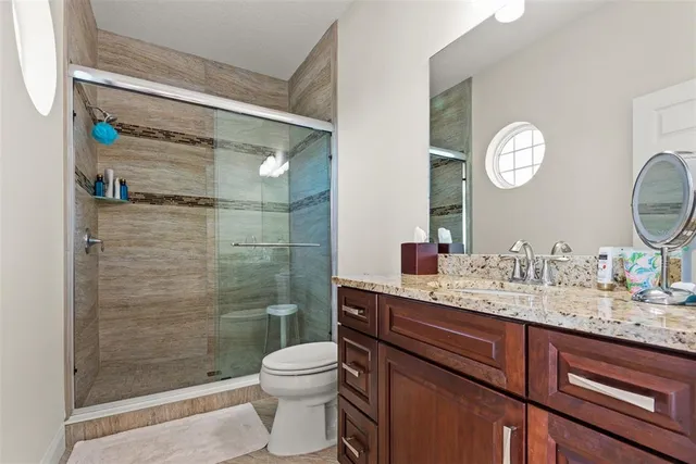 a bathroom with a granite countertop toilet a sink and a mirror