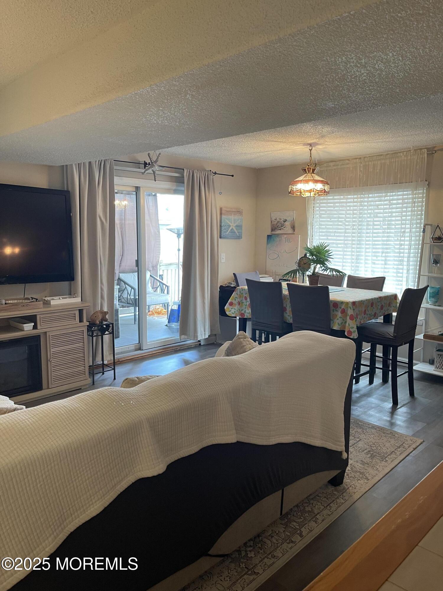 202 Carteret Avenue, Unit A2 Seaside Heights, NJ 08751 - Photo 3 of 15 a living room with furniture a flat screen tv and a dining table with wooden floor