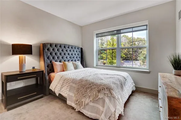 a bedroom with a bed and a tv on next to a window