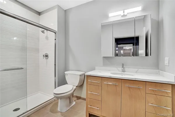 a bathroom with a granite countertop sink toilet a mirror and shower