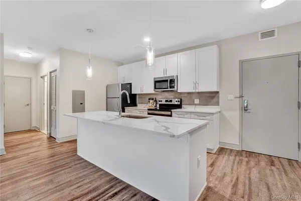 a kitchen with kitchen island white cabinets and stainless steel appliances