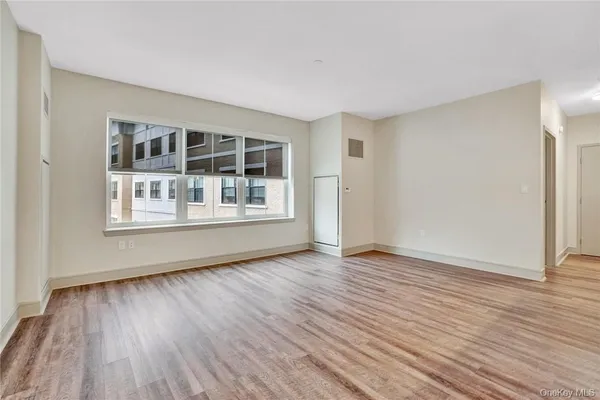 a view of an empty room with wooden floor and a window