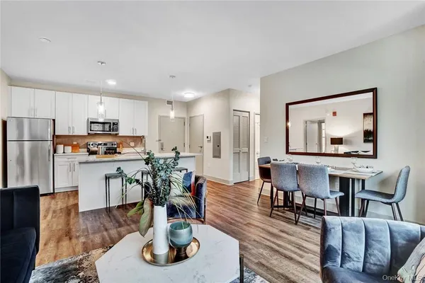 a living room with furniture kitchen view and a wooden floor