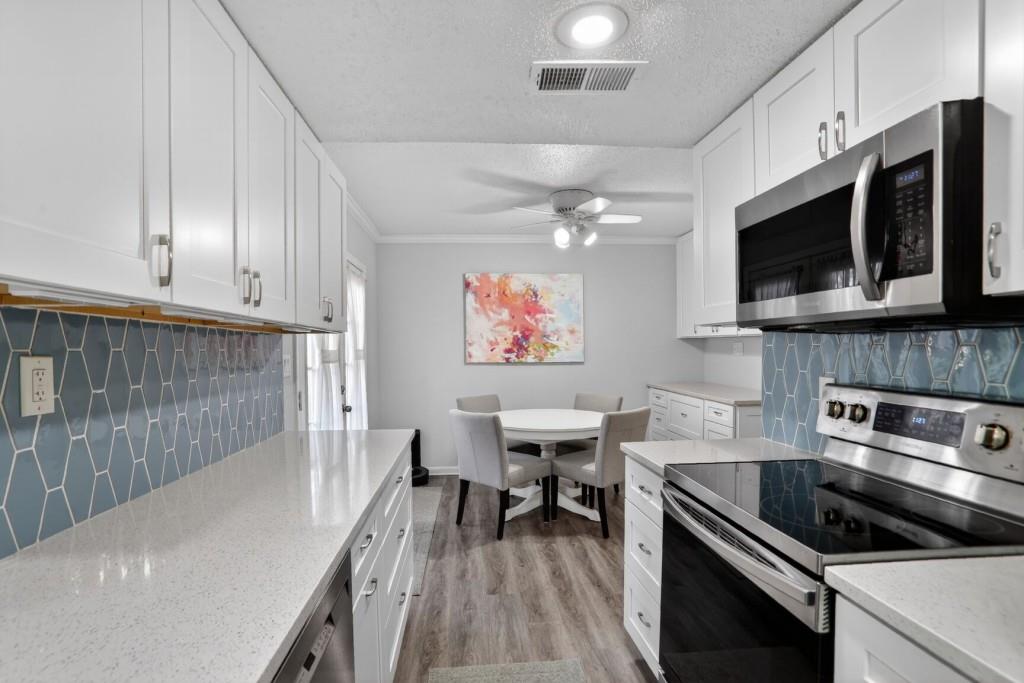 6900 Roswell Road, Unit L7 Atlanta, GA 30328 - Photo 9 of 25 a kitchen with stainless steel appliances a stove a microwave and white cabinets