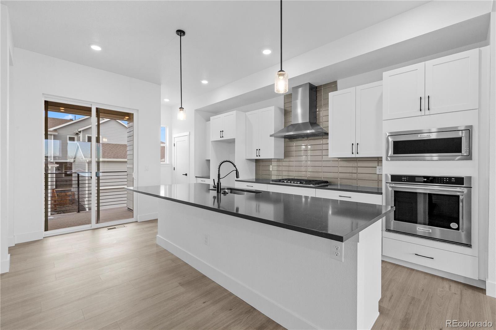 14281 Currant Street Broomfield, CO 80020 - Photo 13 of 23 a large kitchen with granite countertop a stove a sink and a wooden floor