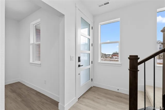 a view of a hallway with wooden floor and a bathroom