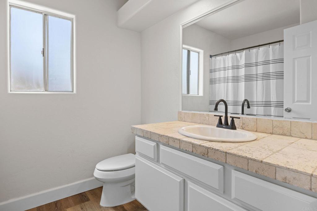 4595 Blackwell Road Oceanside, CA 92056 - Photo 22 of 47 a bathroom with a granite countertop sink toilet and mirror
