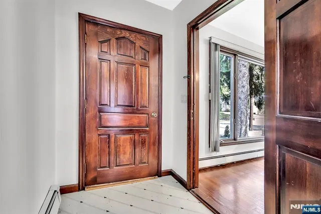 a view of a hallway with wooden floor and a cabinet