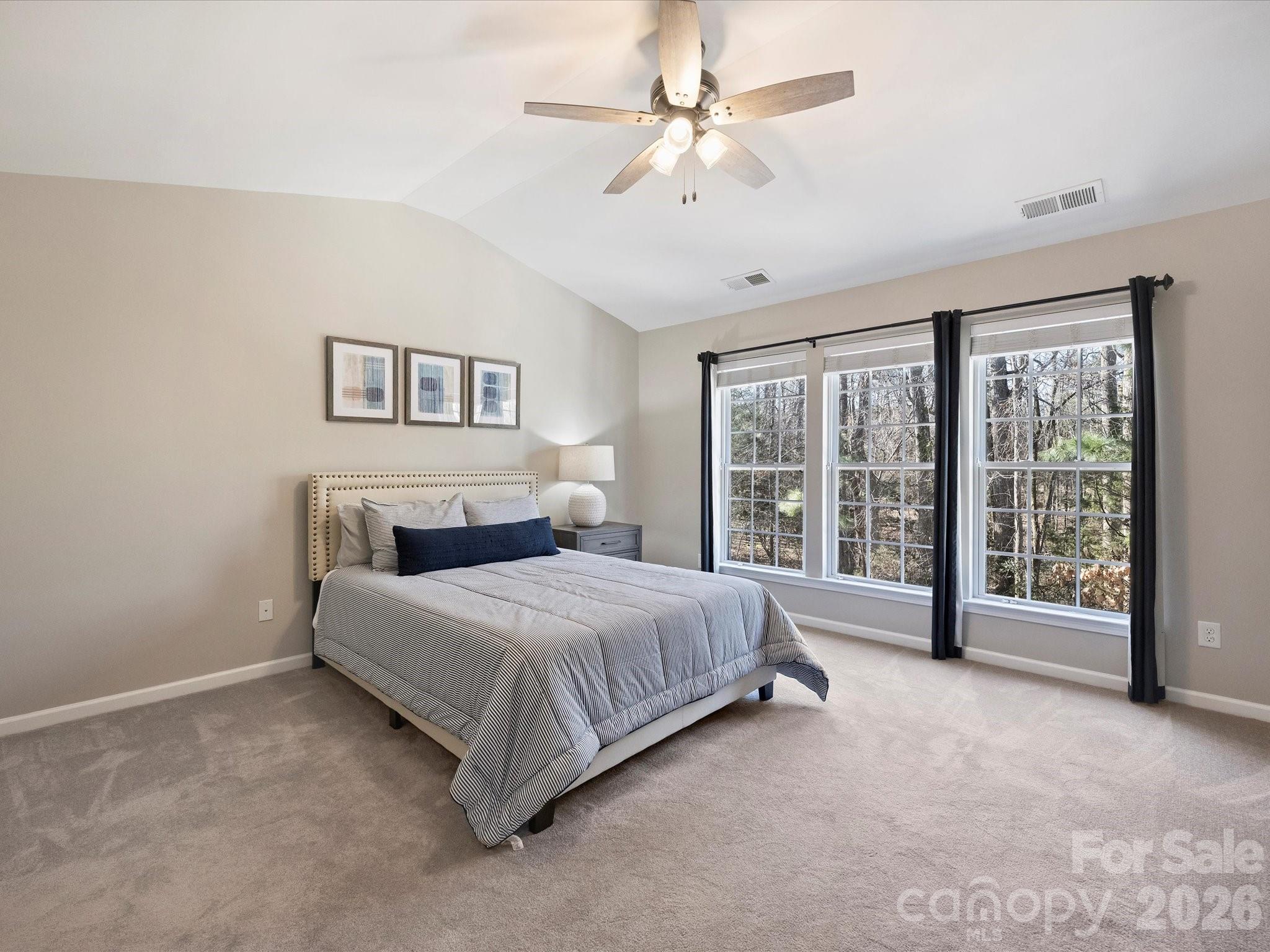 15544 Canmore Street Charlotte, NC 28277 - Photo 24 of 36 a spacious bedroom with a large bed and a chandelier fan