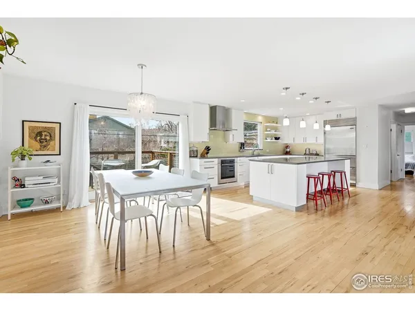 a dining hall with stainless steel appliances kitchen island granite countertop a dining table chairs and a living room view