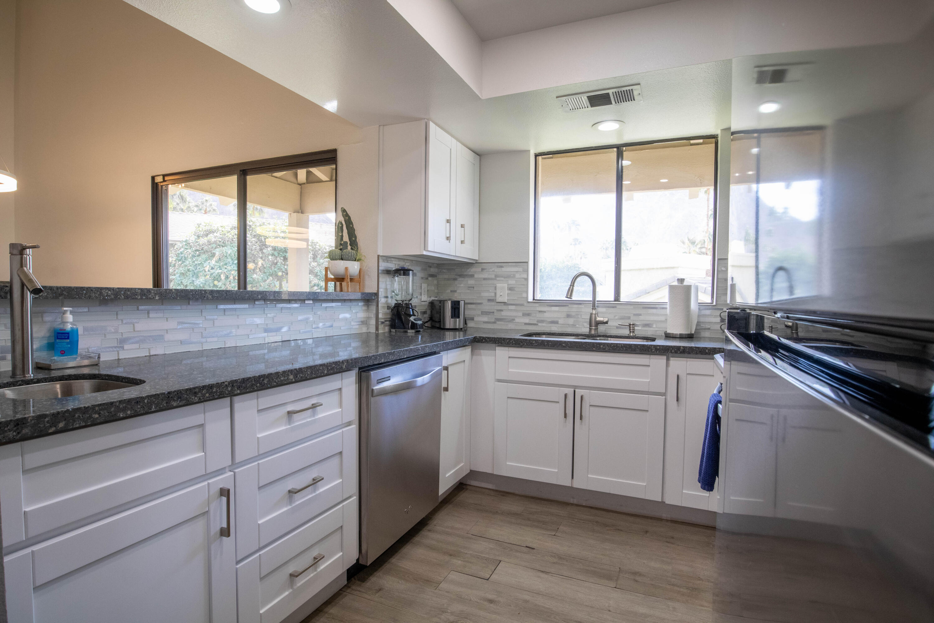 46560 Arapahoe Circle, Unit B Indian Wells, CA 92210 - Photo 7 of 17 a kitchen with granite countertop white cabinets window and stainless steel appliances